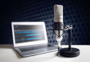 Podcast microphone and laptop computer on desk in recording studio