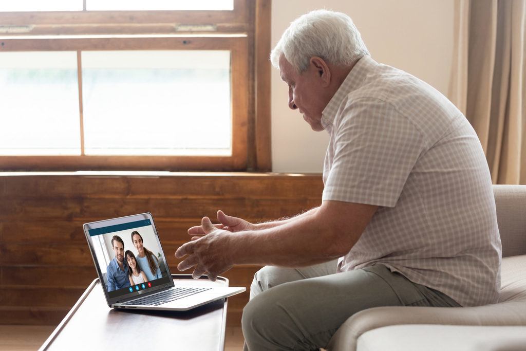 Happy elderly man holding video call with family.