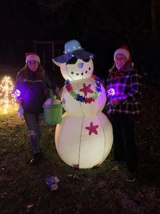 Two people with a beach themed blow up snowman