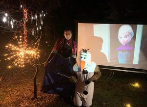 People dressed up as Princess Anna and Olaf posing in front of a movie screen