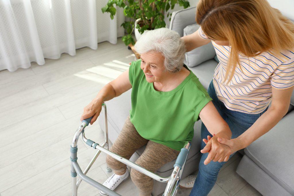 An elderly woman being assisted by her caretaker in a nursing home