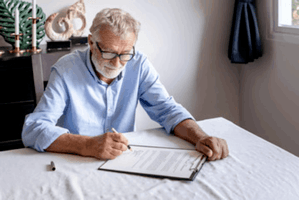 An elderly man signing his last will and testament