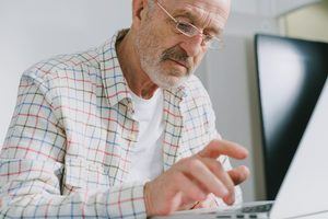 older man typing at computer