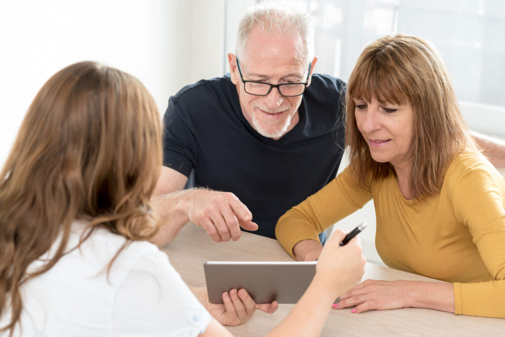 Estate planning attorney giving explanations on tablet to senior couple