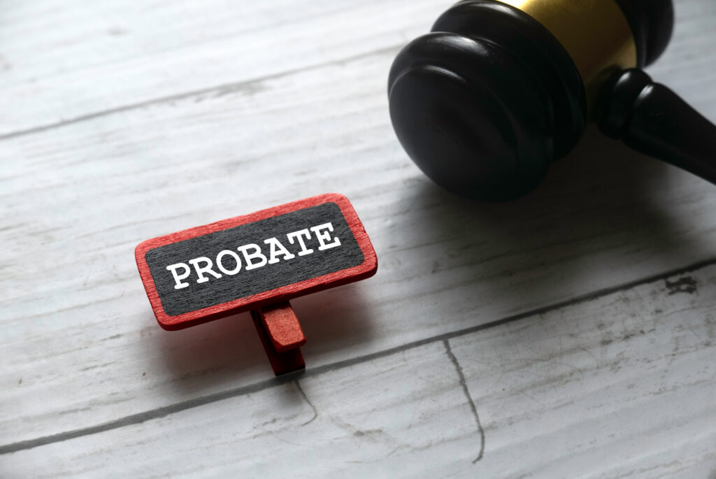 Selective focus of gavel and red tag written with PROBATE on white wooden background.